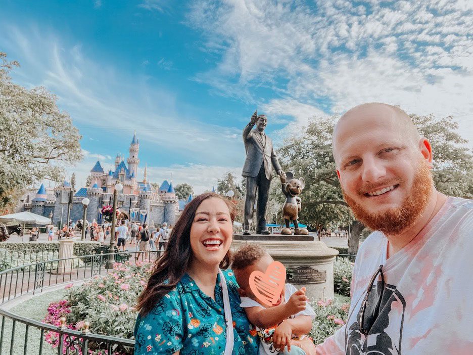parents and toddler smile together at Disneyland