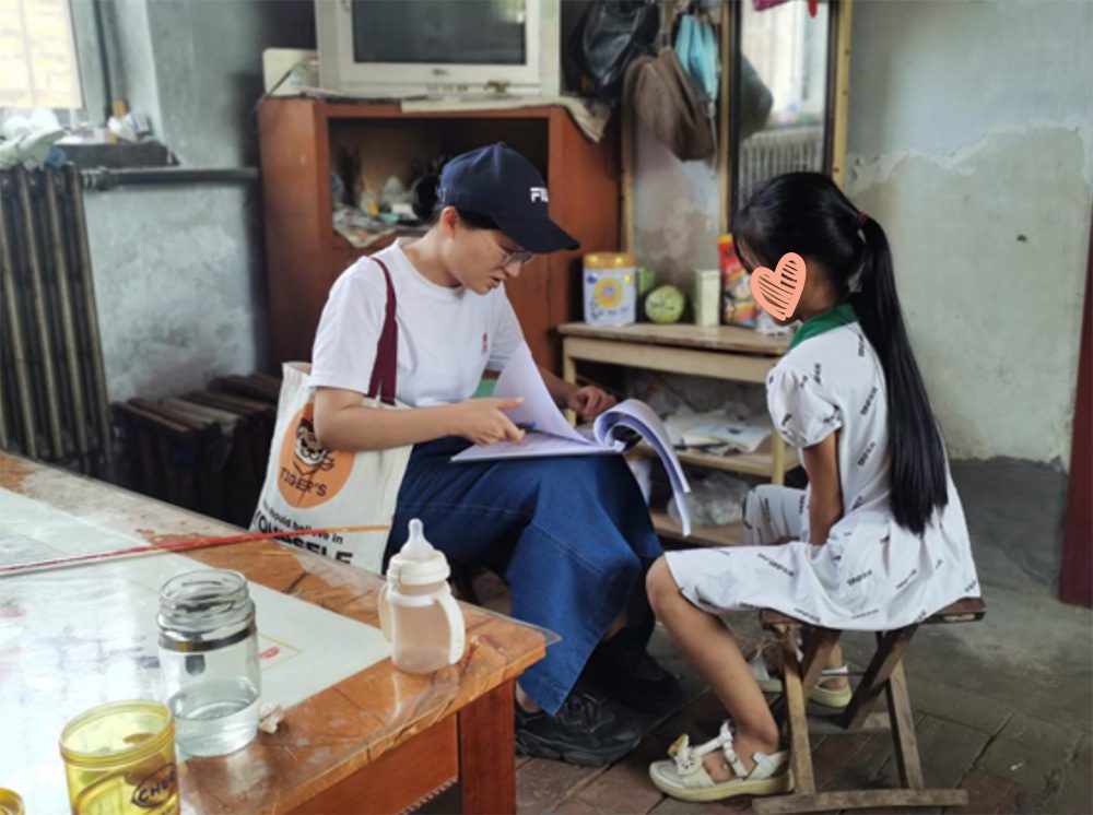 Girl sits on stool and listens to social worker sitting across from her