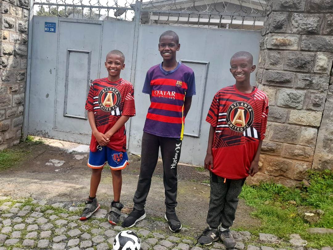 Three boys in Ethiopia post with a soccer ball