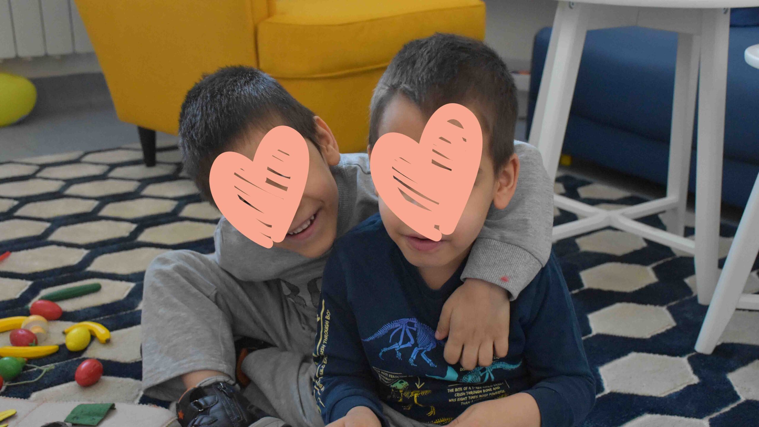 Two boys hug each other while playing on a tiled floor.