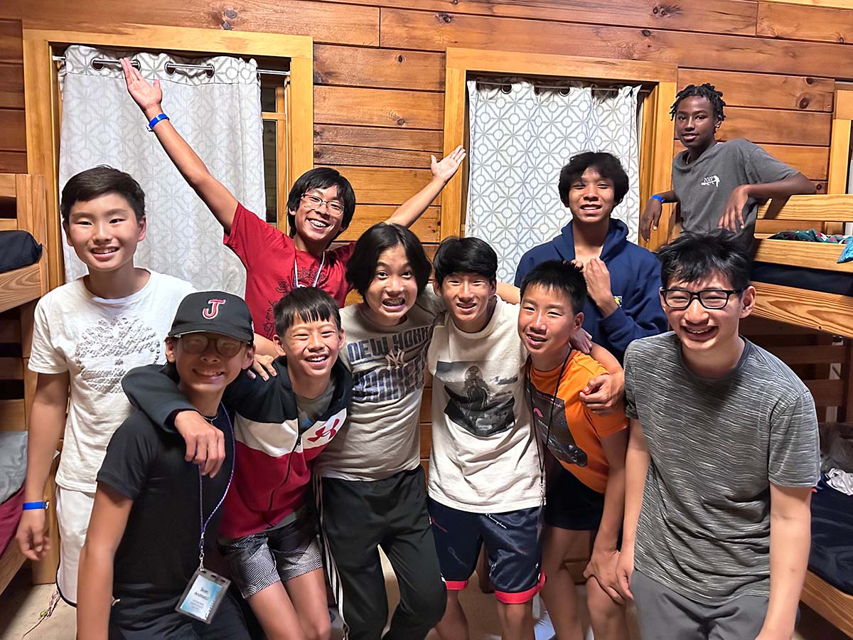 Group of boys smiles for group picture in wood cabin