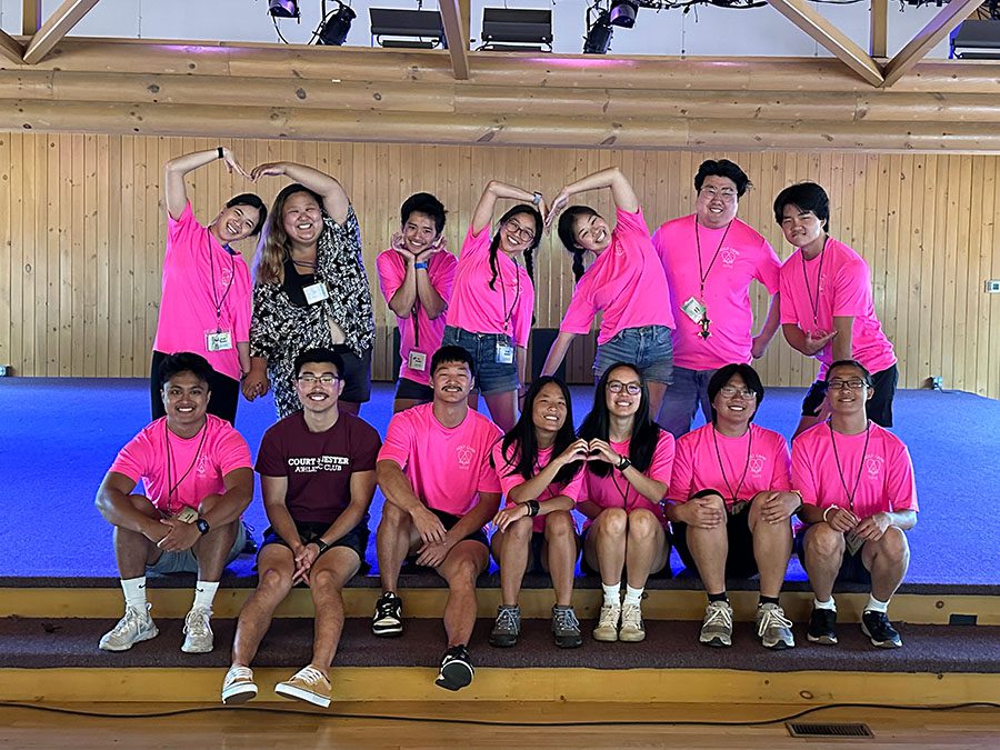 Group of camp counselors in pink shirts smiles during group picture