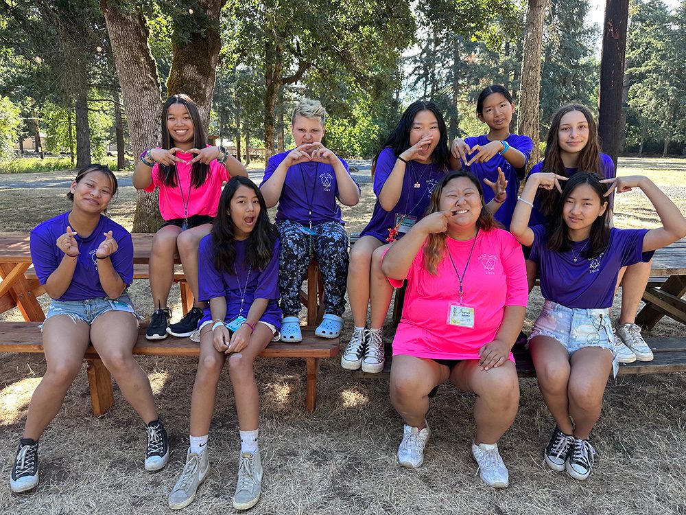 Group of girls make silly faces on picnic table
