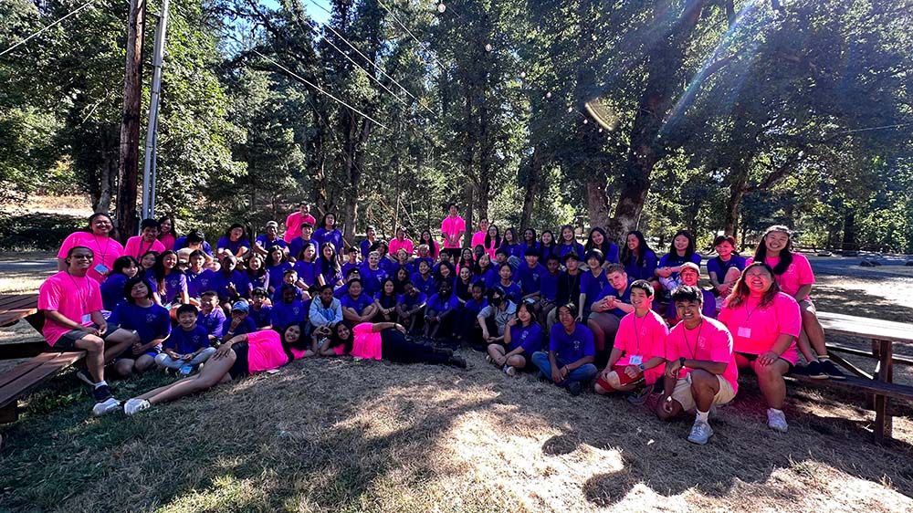 Group photo of campers and counselors in purple and pink t-shirts