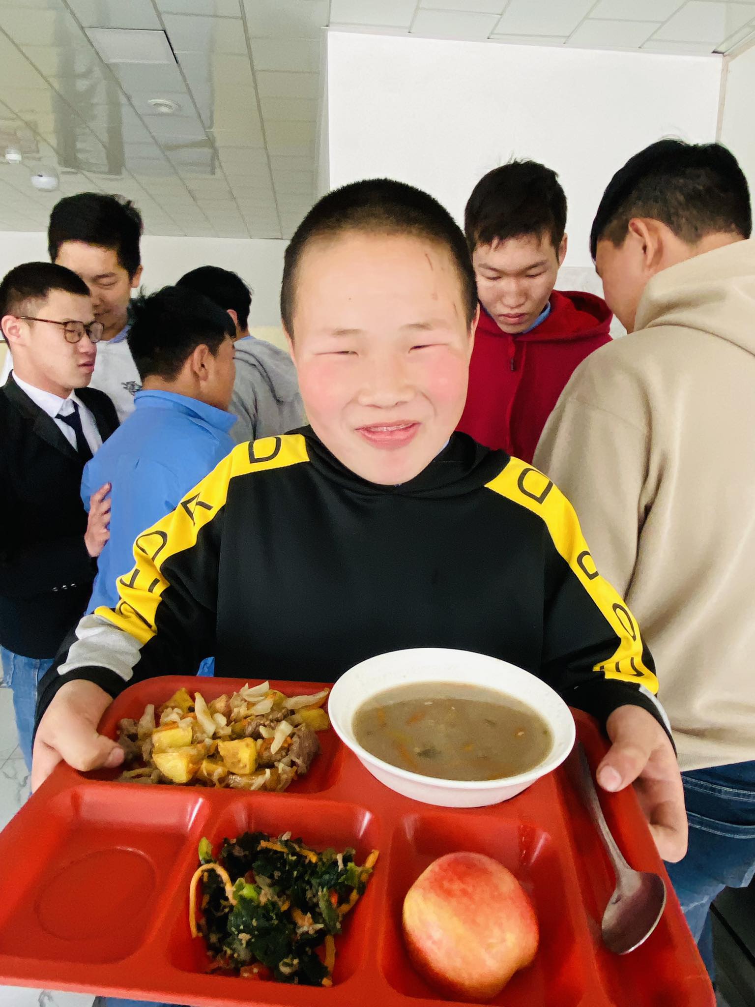 Boy smiles big holding school lunch tray in Mongolia