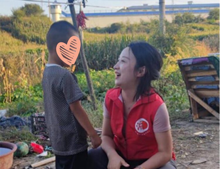 Social worker in red vest smiles at little boy