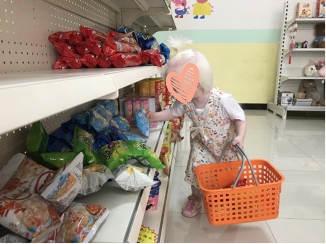Little girl picks up snack from grovery store shelf