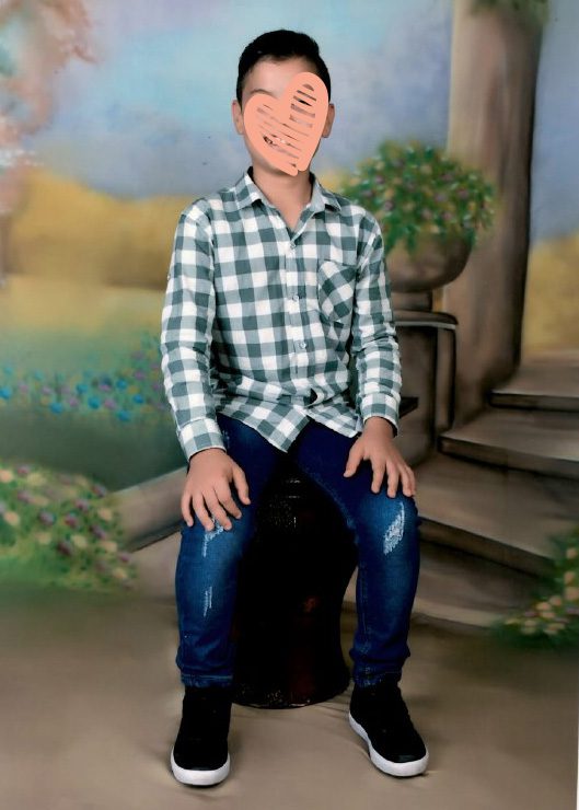 Child in collared shirt sitting and smiling