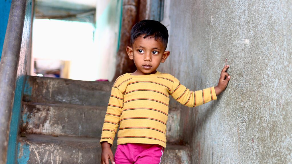 Sweet child in striped yellow shirt walking down a stairwell.