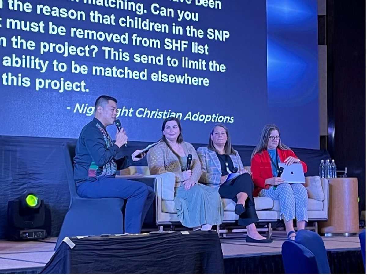 Group of people sit on a couch on a stage for a panel interview