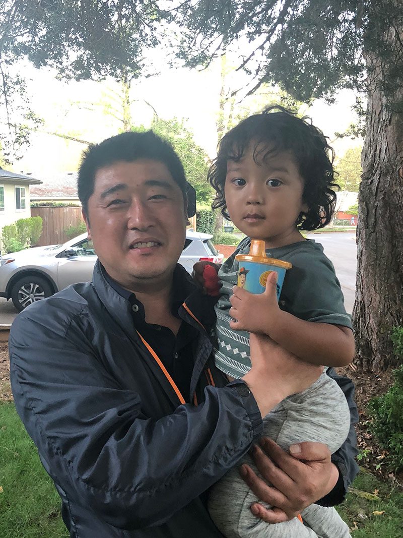 Korean man holds a baby with a sippy cup