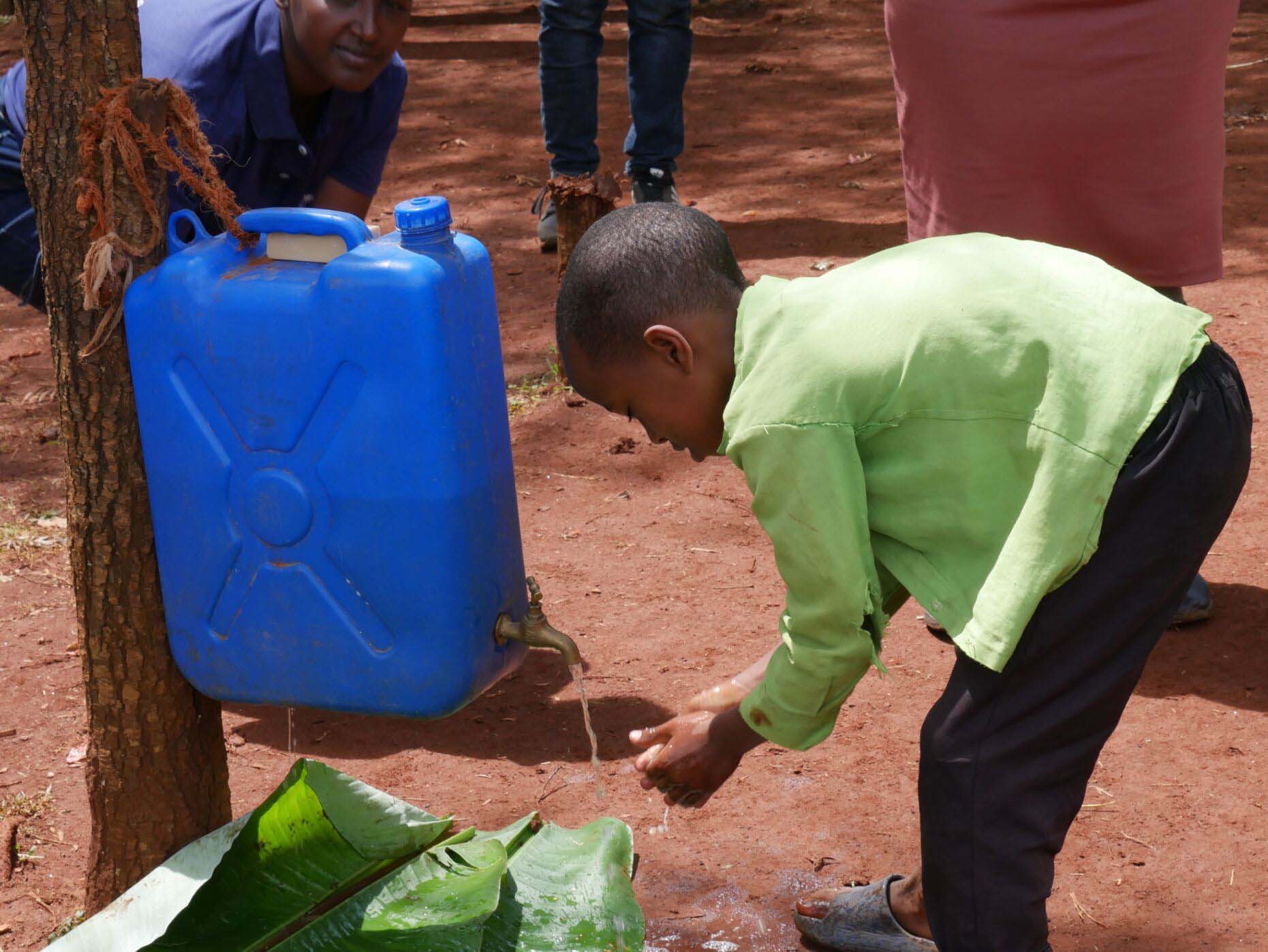 Child stoops to wash hands outside