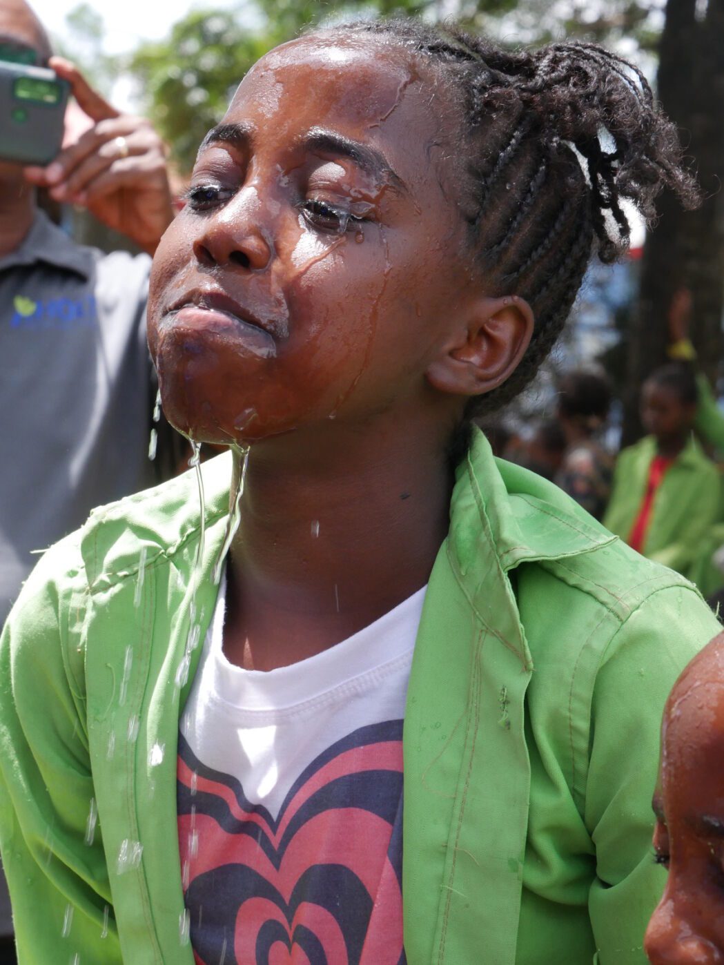 Girl in green shirt smiles with her face covered in water