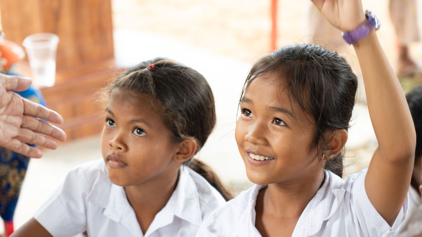 Young female student raising her hand and smiling