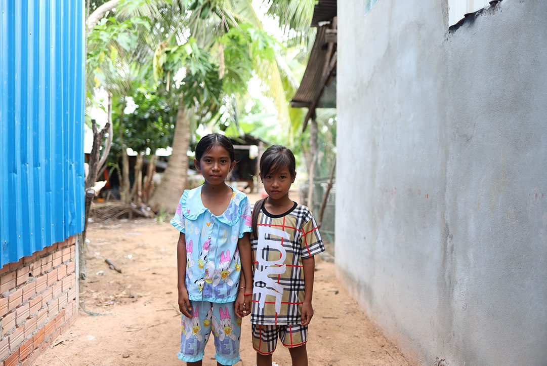 Two girls stand in an alleyway in Cambodia