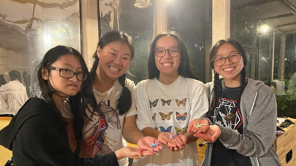 Group of girls holds up origami and smiles