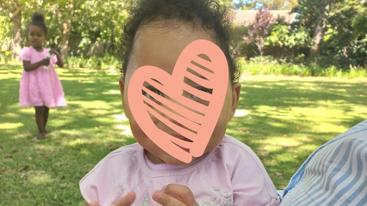 Little girl in pink shirt smiles at the park