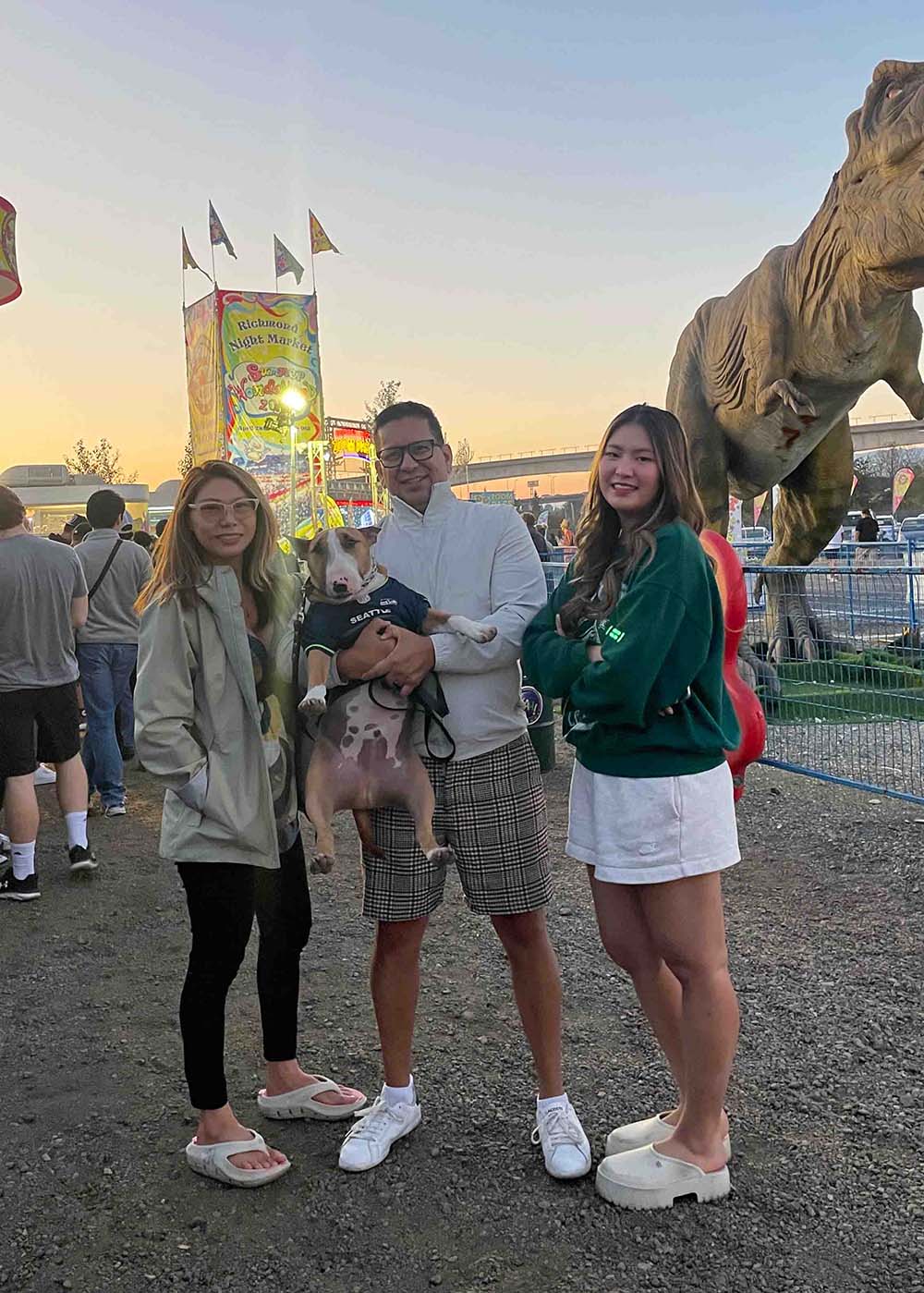 Family with dog stands outside at fair and smiles