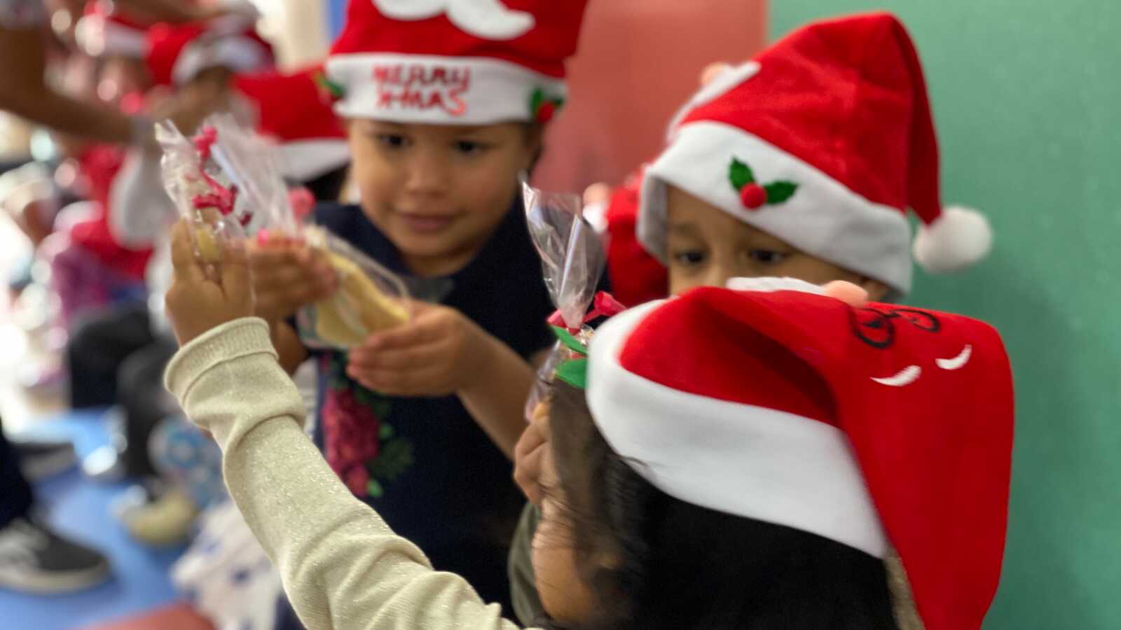 kids in Santa hats hold cookies