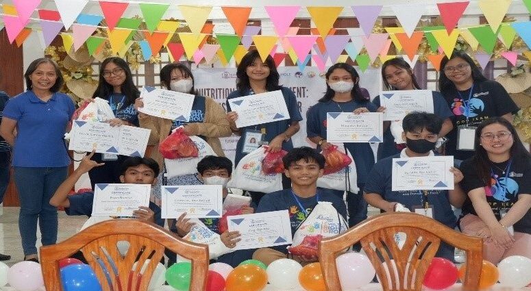 A group of students gather in a colorful classroom with certificates