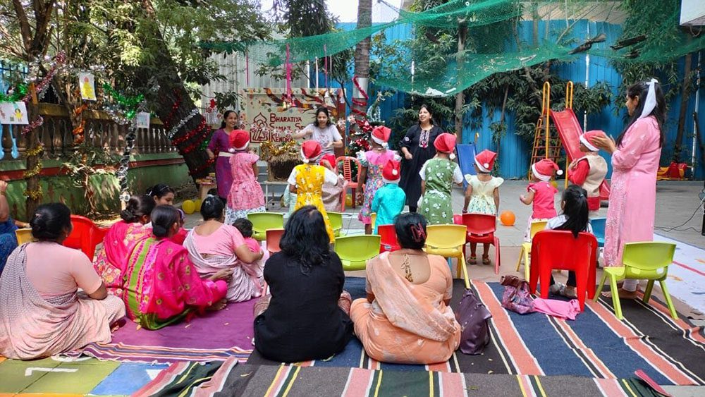 Group of moms and kids in Santa hats gather outside for a Christmas party