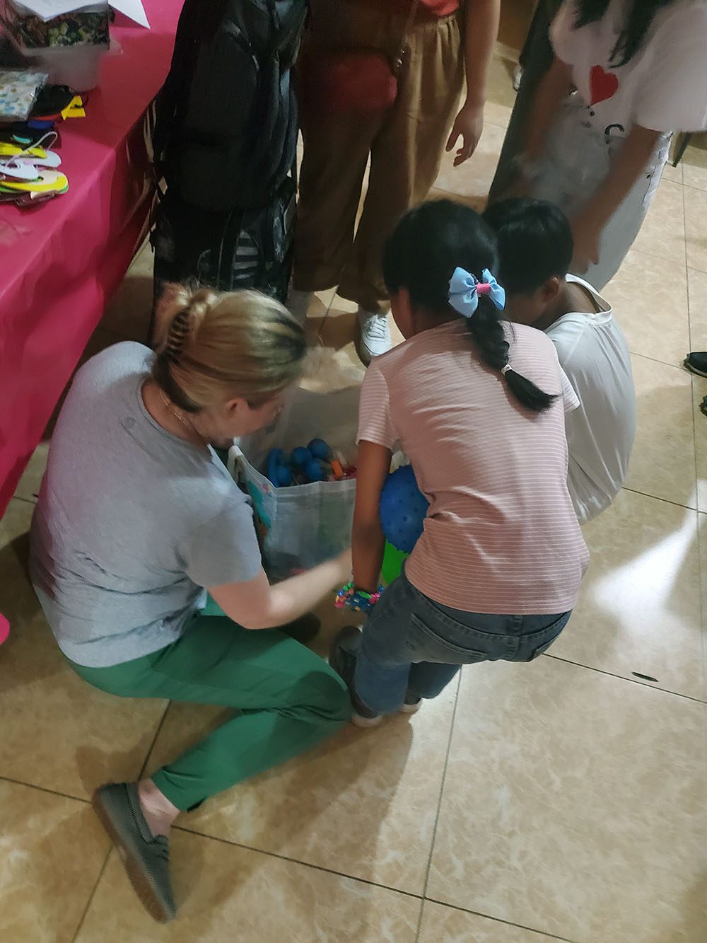 A woman and several children play with toys on the ground