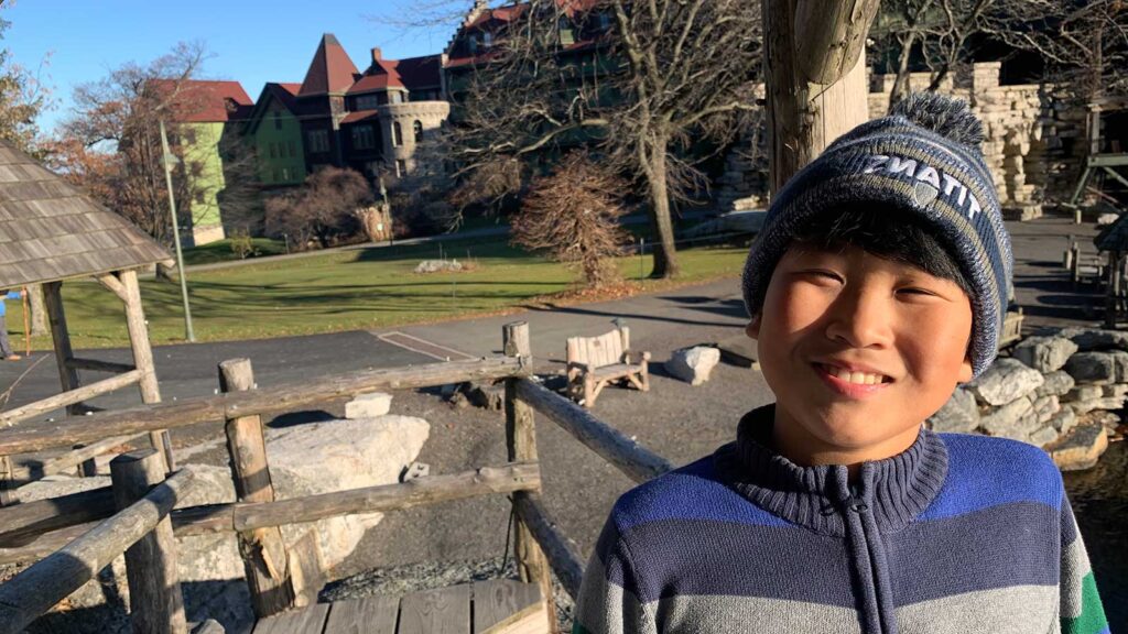 Young boy smiling in front of wooden fence