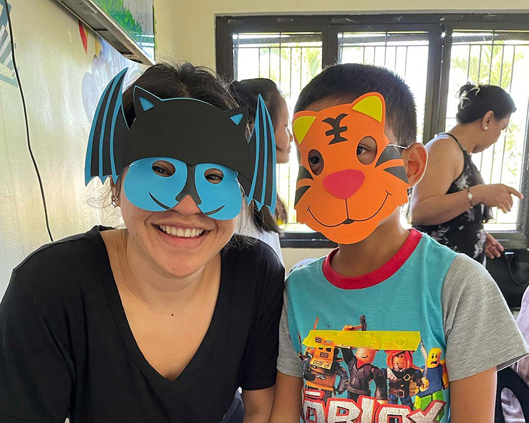 A social worker and child take a photo with animal masks on