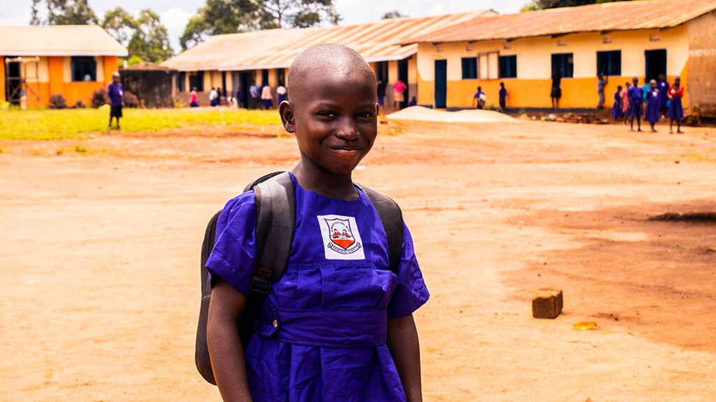 A girl in uganda smiles at her school