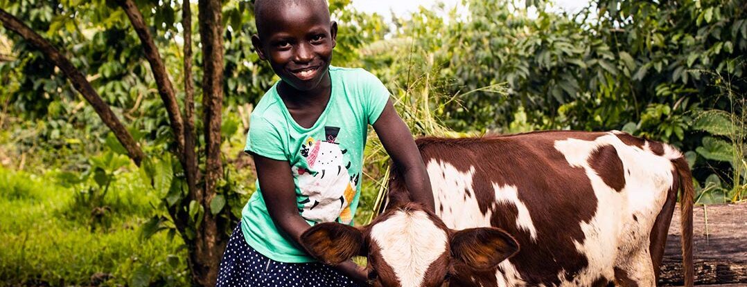 A girl in Uganda poses with a baby calf