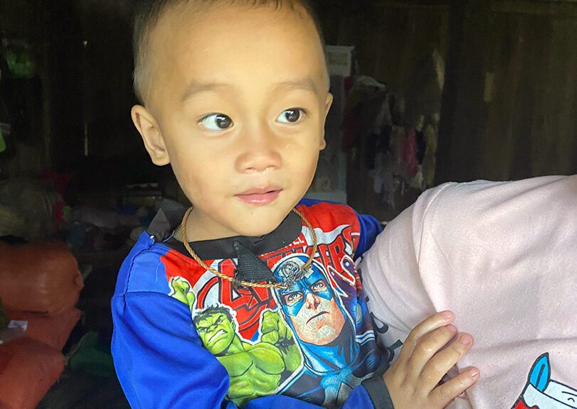 A little boy is held by his mom inside their house