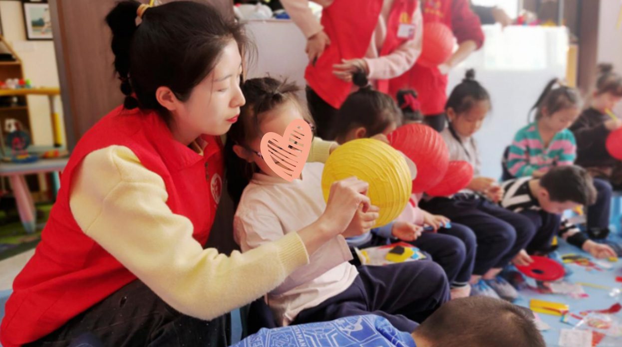 A young woman holds a little girl who is making a red lantern