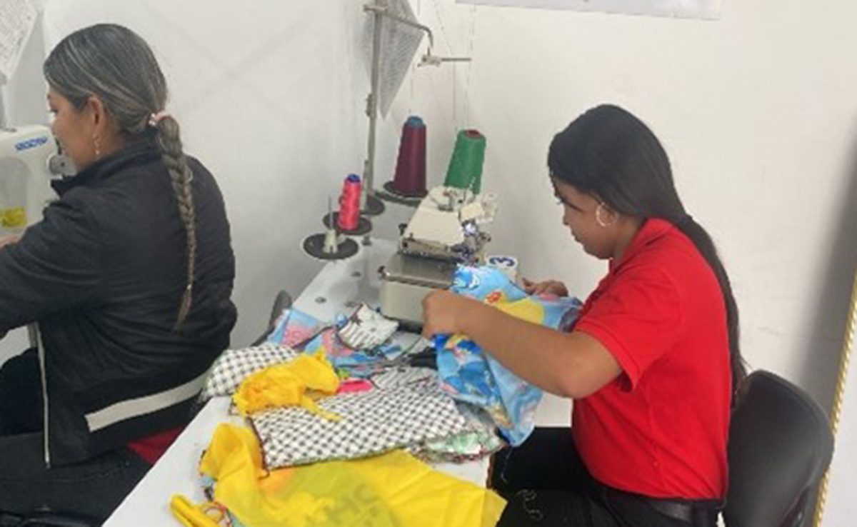 A young woman sits and works at a sewing machine