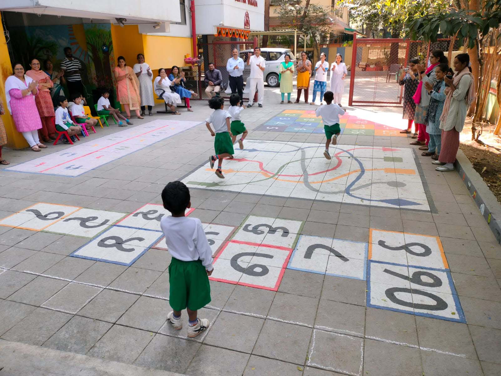 A group of little kids gather to play games outside with their mothers watching