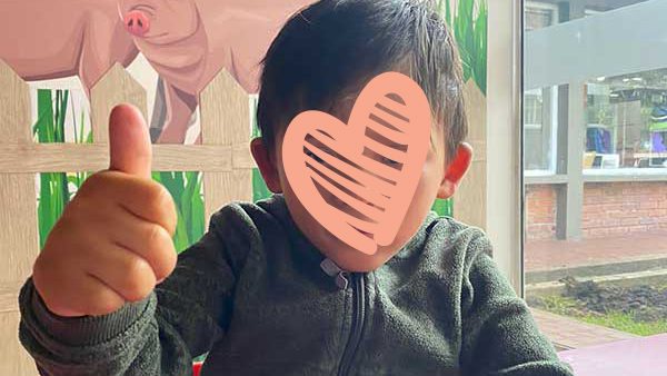 Little boy sits in a nursery room and gives a thumbs up