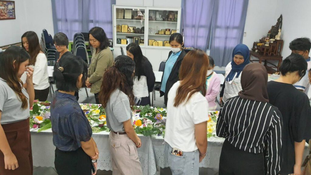 A group of people gathers in a room to look at arts and crafts