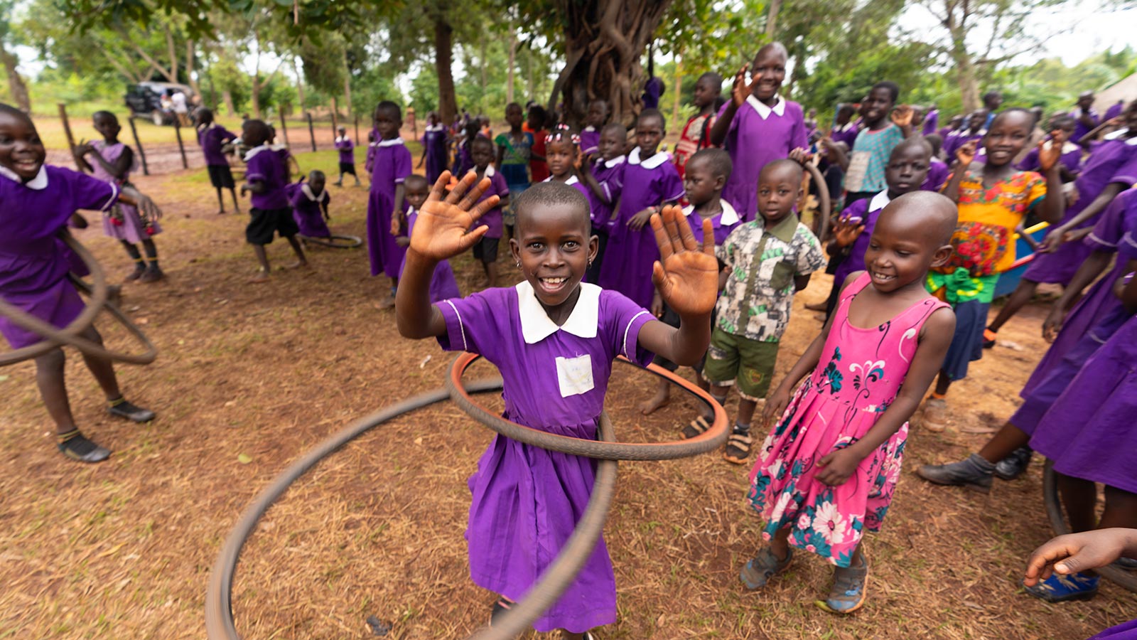 Schoolgirl in Uganda playing hula hoop in purple school uniform