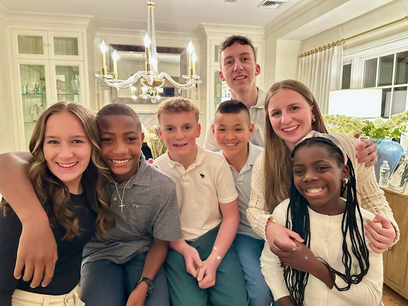 a group of siblings smiles all together with their adopted brother who recently came home