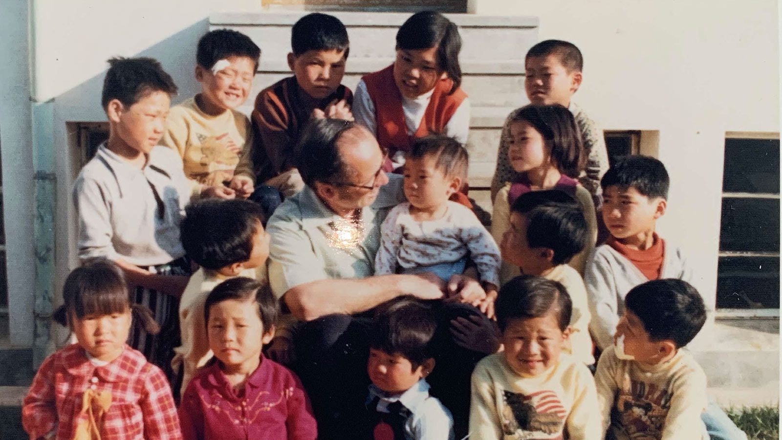 Hollee McGinnis wears red plaid suit in a group photo taken at her orphanage in Korea