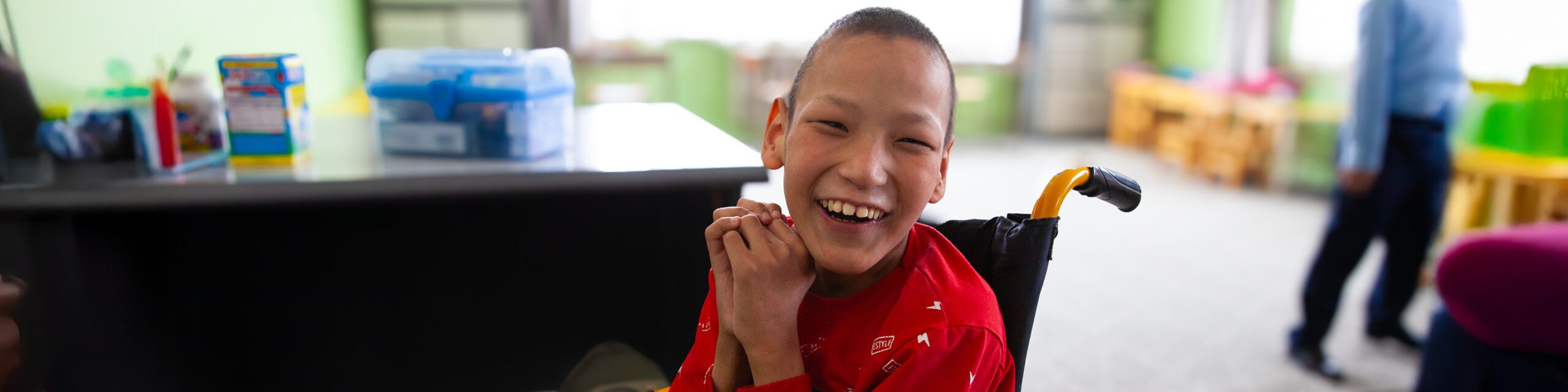 Happy, smiling boy in a wheelchair at school